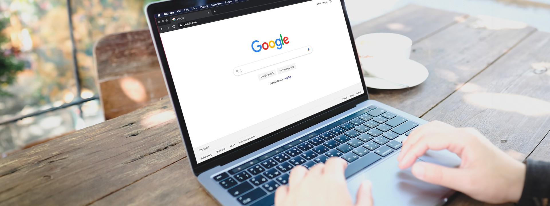 A person typing on a laptop with the google logo on it.