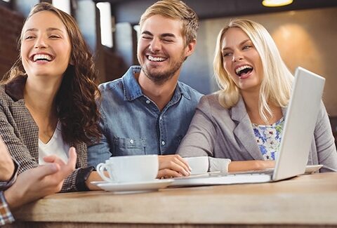 A group of friends laughing at a table in a coffee shop.